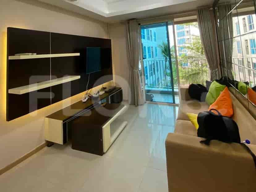 A modern living room featuring a dark wood accent wall with integrated shelving and lighting, a low-profile media console, and a large sliding glass door leading to a balcony.