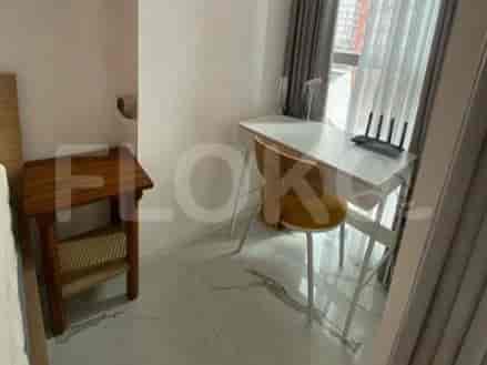A small desk with a chair and a router near a window with curtains.