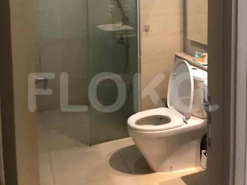 A modern bathroom featuring a toilet with the seat up and a shower stall.