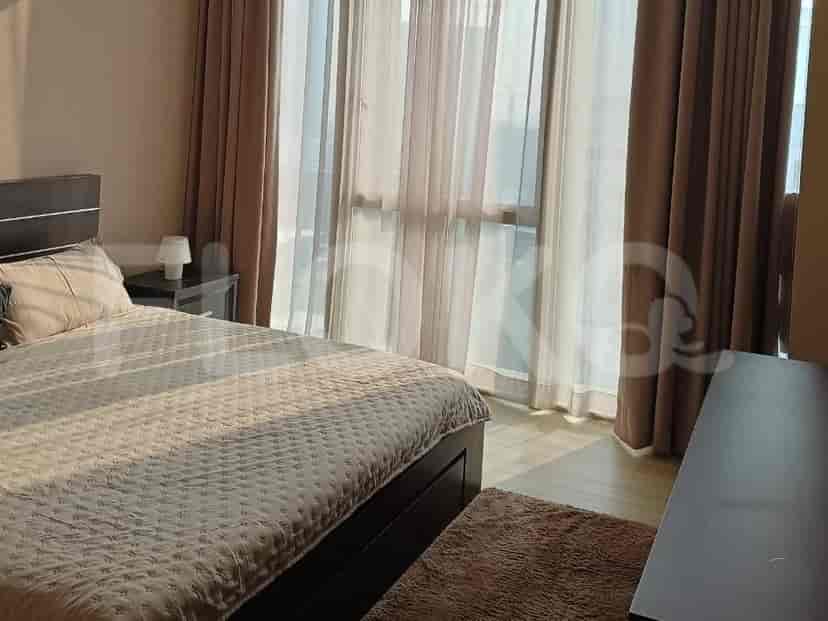 Bedroom with a queen bed, a wooden side table, and large windows.