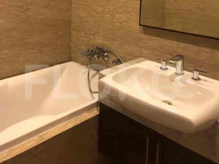 A bathroom with a bathtub, a sink with a vanity, and marble wall tiles.