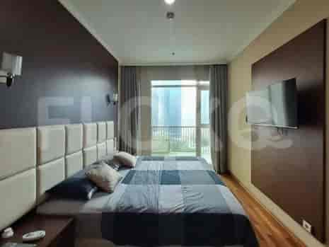 Kamar tidur dengan tempat tidur tunggal, meja, dan lemari besar dengan pintu cermin.