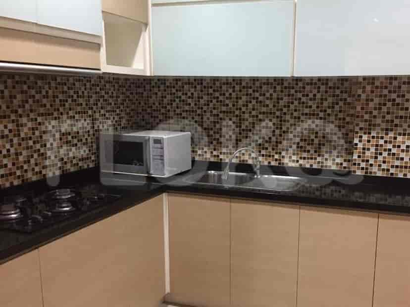 Meja dapur dengan microwave, wastafel, dan kompor gas.
