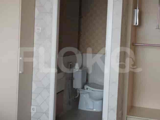 Kamar mandi kecil dengan toilet dan bidet, dilihat melalui pintu yang terbuka.