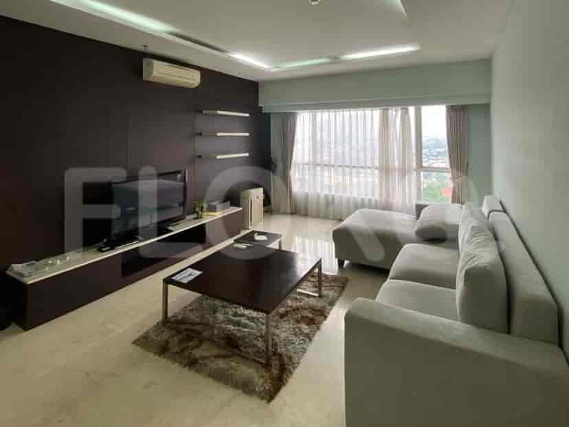 A modern living room with a large L-shaped sofa, a coffee table on a rug, and a wall-mounted TV.