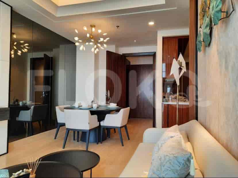 A modern living room with a dining table, sofa and kitchen area visible.