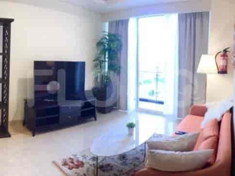 A contemporary living space with a sofa, a TV, and large windows offering an outdoor view.