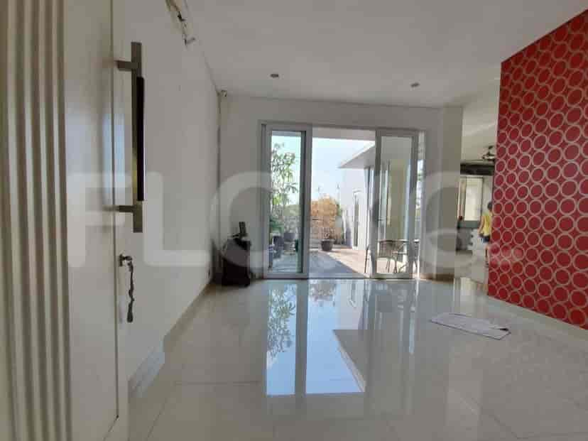 Ruang tamu dan ruang makan terbuka dengan lantai ubin, pintu kaca geser besar, dan dapur modern di latar belakang.