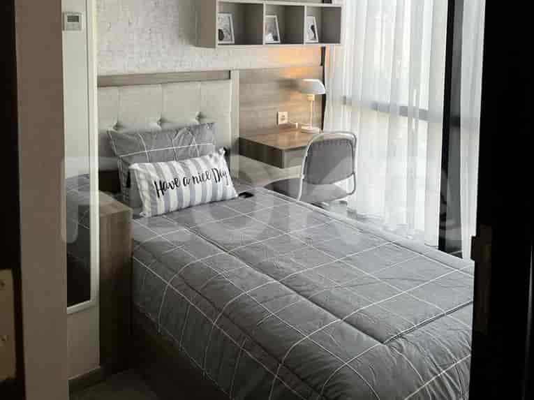 A single bed in a room with a built-in desk and shelving unit.