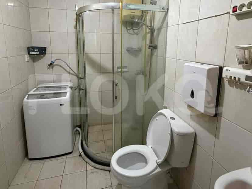 Sebuah kamar mandi dengan bilik shower, toilet, dan mesin cuci.