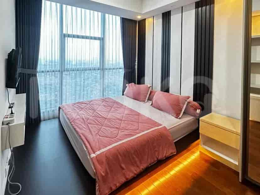 Sebuah kamar tidur dengan tempat tidur ukuran queen, seprai merah muda, dan jendela besar dengan gorden gelap.