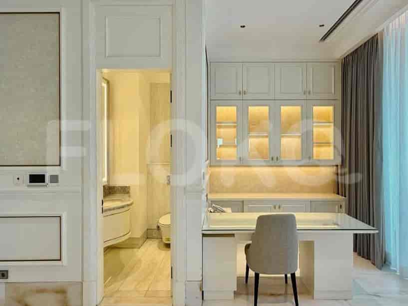 A home office area with a desk, chair, and built-in cabinets, next to a bathroom entrance.