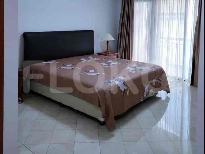 A bedroom with a queen-size bed, bedside table, and lamp.