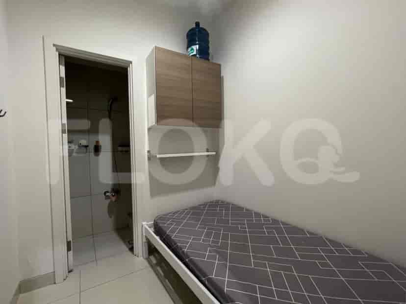 A small bedroom with a single bed and a view into a small bathroom.