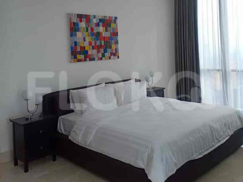 A bedroom with a bed, colorful artwork, and nightstands.