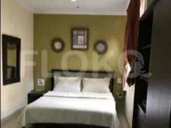 A bedroom with a queen-sized bed, dark wooden nightstands, and a mirror.