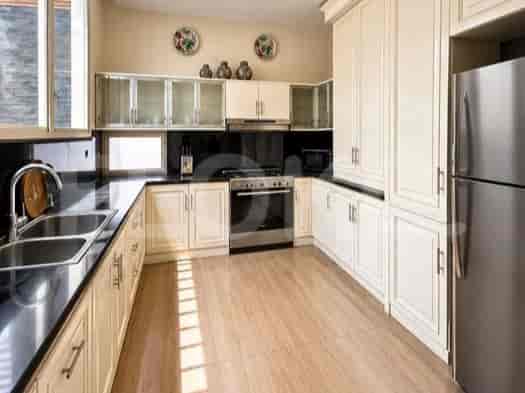 Dapur luas dengan lemari berwarna krem, meja granit, dan peralatan stainless steel.