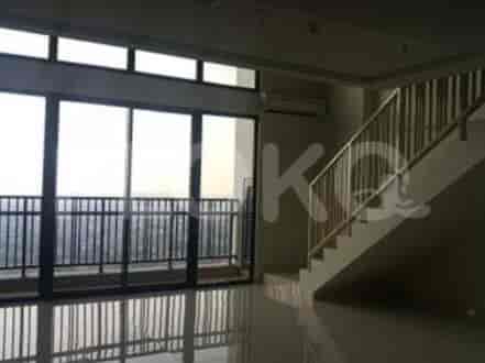 A view of a living room with large windows overlooking a city view, a staircase, and an air conditioning unit.