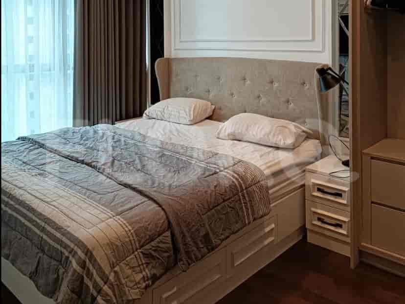 Kamar tidur yang menampilkan tempat tidur dengan sandaran kepala berlapis, meja samping tempat tidur, dan gorden.