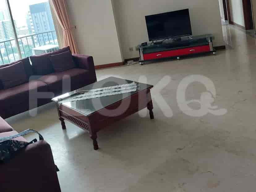 A living room with a maroon sectional sofa, a dark wood coffee table, and a TV stand with a television on it.