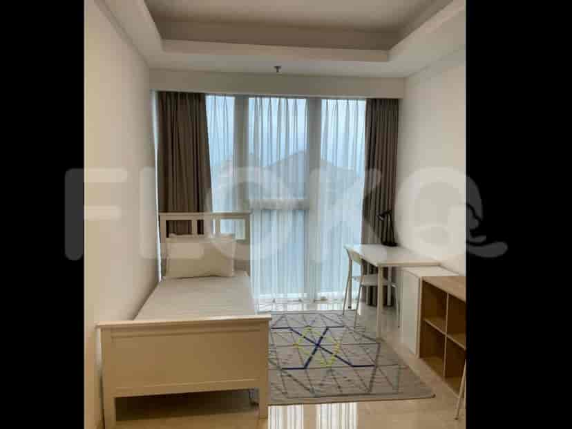A bedroom with a single bed, a desk and chair, and a window with curtains.