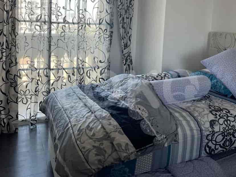 Bedroom featuring a bed with patterned bedding and sheer curtains.