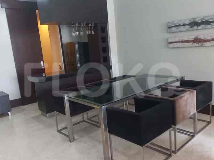 Dining area with a glass table, chairs and a refrigerator.