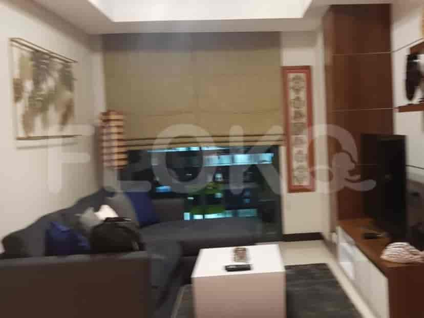 Ruang tamu dengan sofa sectional abu-abu gelap, meja kopi putih, dan jendela besar.