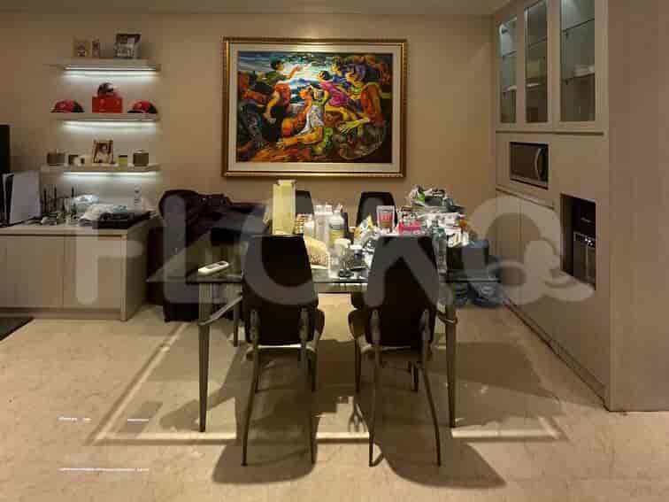 A dining area with a glass-top table, chairs, and a large artwork.