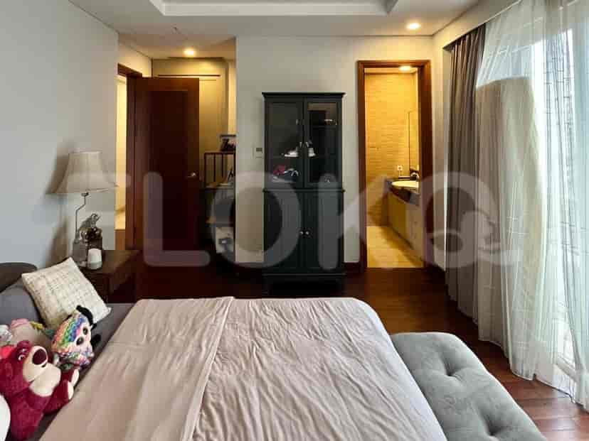 A view into a bedroom and an adjoining bathroom, featuring a bed, a cabinet, and marble-clad bathroom.