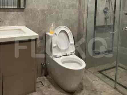 Kamar mandi bersih dengan toilet, wastafel, dan pancuran tertutup kaca.