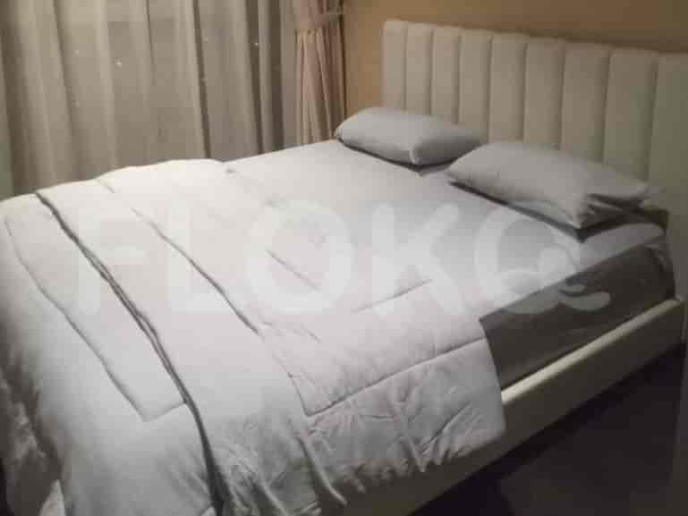A bed with white bedding and a large white headboard, bedside table, and lamp.
