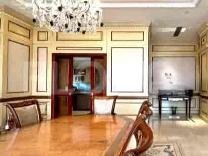 Dining room with large dining table, chandelier, and decorative buffet.