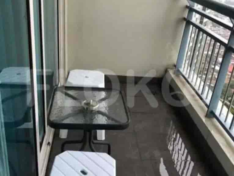 A balcony with a glass-top table and two stools.