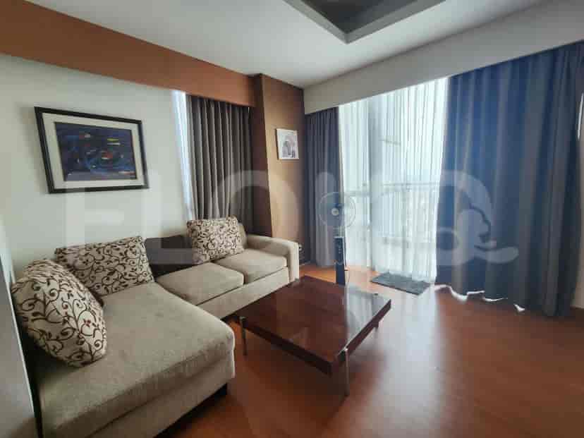 A living room with a sectional sofa, a coffee table, and large windows with curtains.