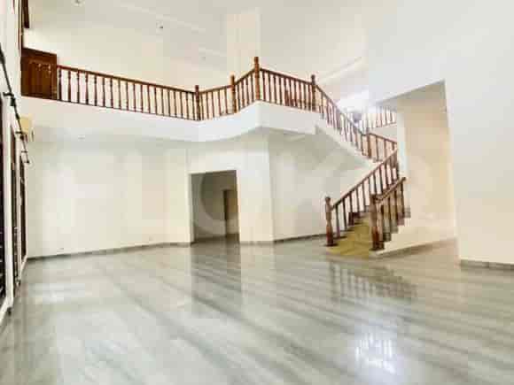 A grand living area with a double-height ceiling, marble flooring, and a wooden staircase.