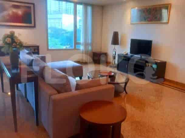 A living room with a large grey sectional sofa, a coffee table, a TV stand with a TV, and a large window.