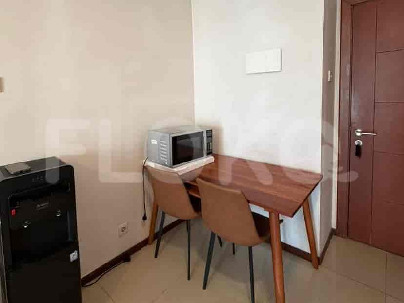 A small dining area with a wooden table, two chairs, a microwave, and a water dispenser.
