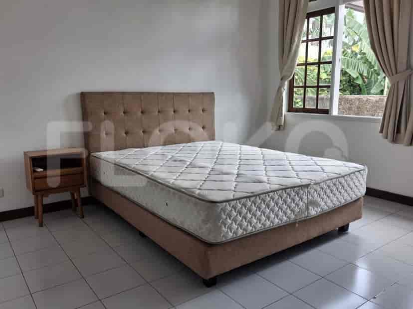 A bedroom featuring a queen-size bed, a wooden nightstand, and beige curtains.