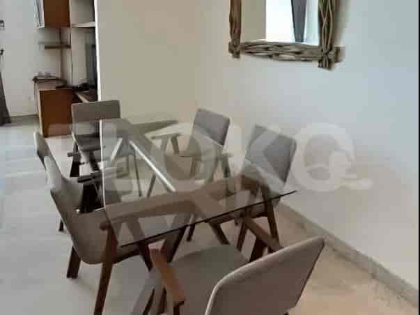 A dining area with a glass-top table and four grey upholstered chairs.