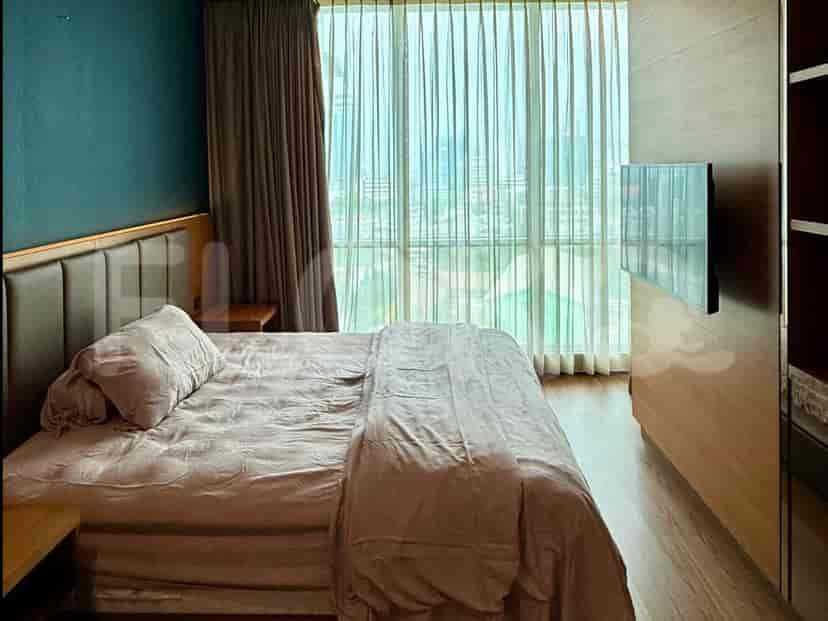 A bedroom with a large bed, a floor-to-ceiling window with sheer curtains, and a wall-mounted TV.