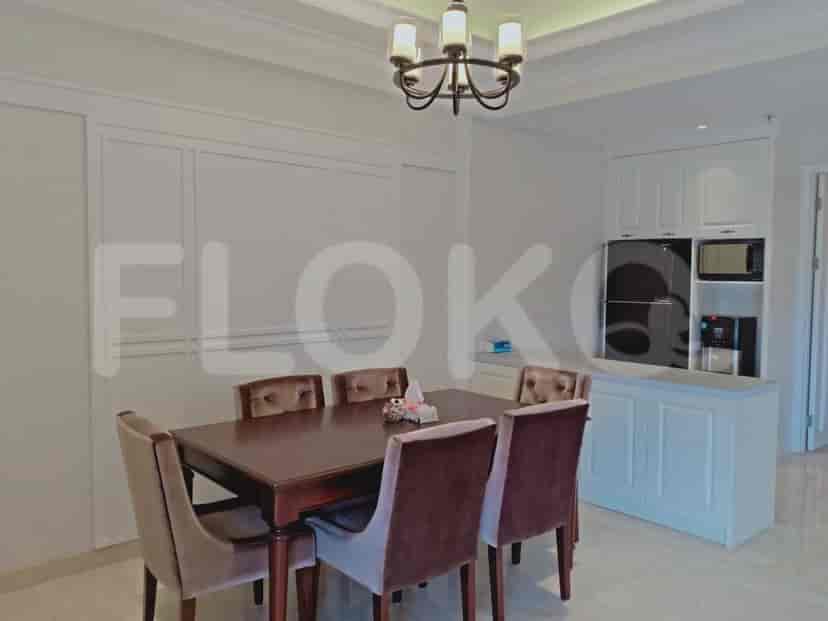 A dining area with a dark wood table, upholstered chairs, and a white cabinet with appliances.