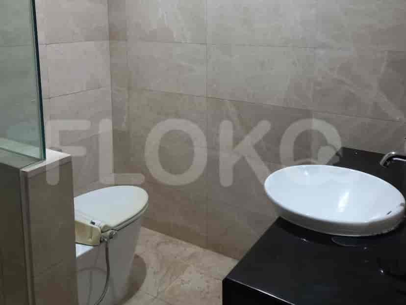 A bathroom with a modern toilet and a white vessel sink on a black countertop, with large beige marble tiles.