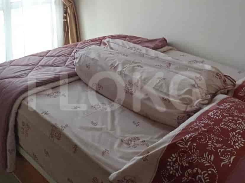 Sebuah kamar tidur dengan tempat tidur, bantal, dan sprei.