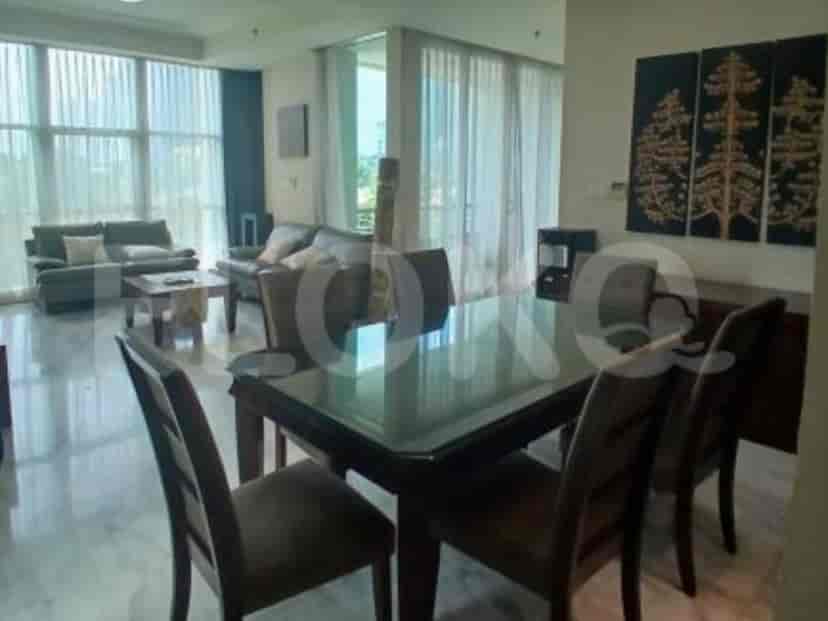 A dining room with a large wooden table and chairs, adjacent to a living area.