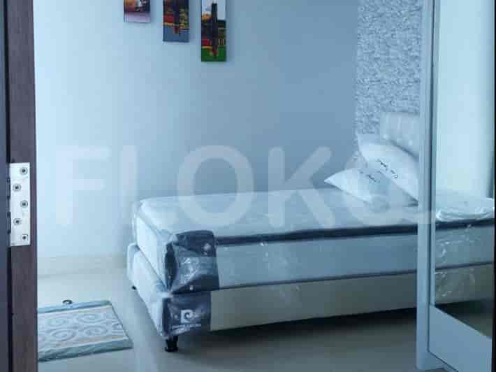 A minimalist bedroom with a bed, artwork, and a small rug.
