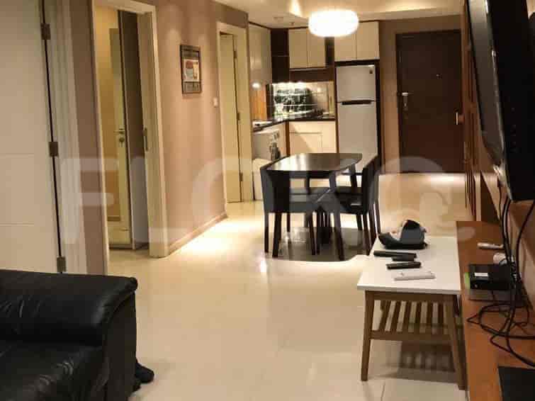 Living room with dining table, kitchen access, and entryway with open doors.