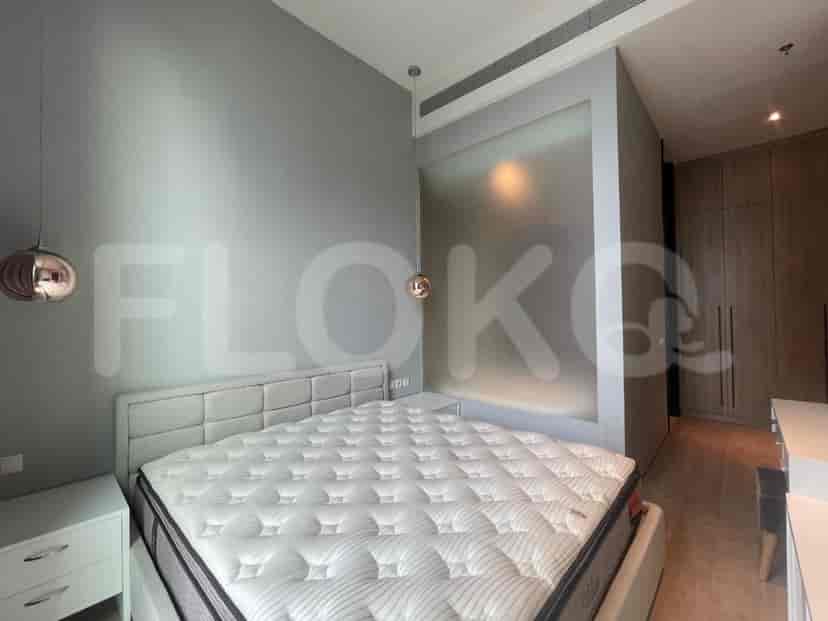 A bedroom featuring a large bed, bedside tables, and a frosted glass partition.