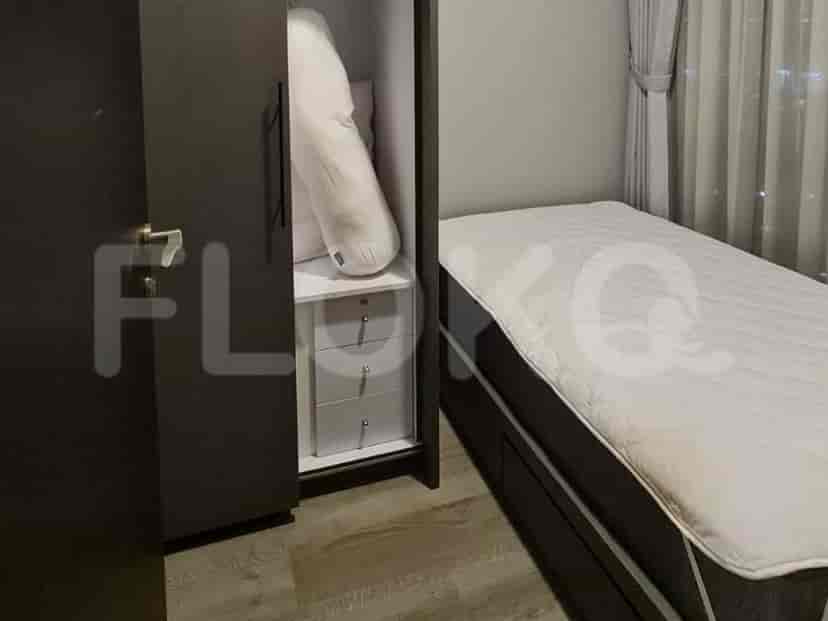 A bedroom with a single bed, an open wardrobe showing storage shelves and drawers, and a window with curtains.