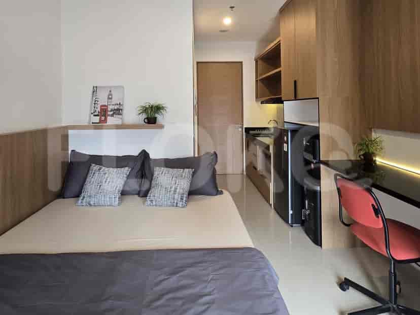 A compact studio apartment featuring a bed, a small kitchenette, and a workspace.